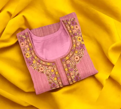 Soft pink silk kurta featuring intricate floral thread embroidery and sequin work on the neckline. This custom-stitched ladies suit is neatly folded and displayed on a vibrant yellow background, showcasing the professional ladies tailoring services and designer neck patterns offered by Tailorboutiques.com.