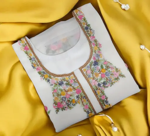Brand new pure white kurti made of ladies fashion clothing with multi-colour fancy thread floral embroidery on a round shaped neck. This ready to wear custom stitched dress piece has been folded and presented on a pure golden yellow silk material to display the excellence of our customised women clothing designer boutiques and designer stitching by Tailorboutiques.com.