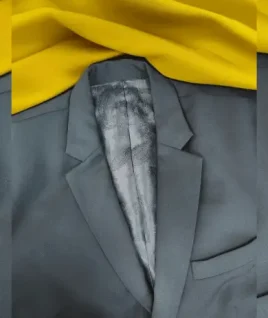 Premium charcoal grey men's coat featuring a sharp notch lapel and luxurious patterned inner lining. This custom-stitched suit jacket is displayed on a yellow fabric background, representing the high-quality gents' tailoring and bespoke coat pant stitching services provided by Tailorboutiques.com.
